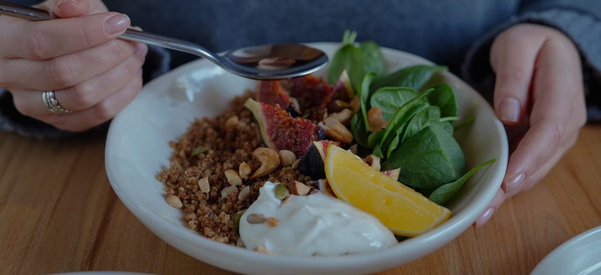 A vibrant brunch bowl with fruit, greens, and nuts for a nutritious meal.