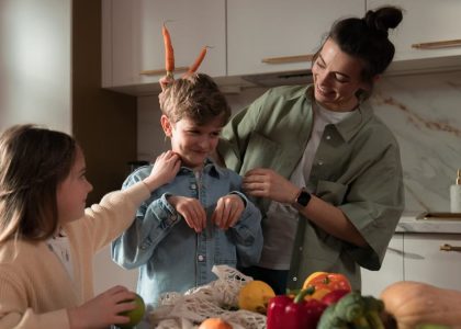Mother and children have fun unpacking vegetables in the kitchen.